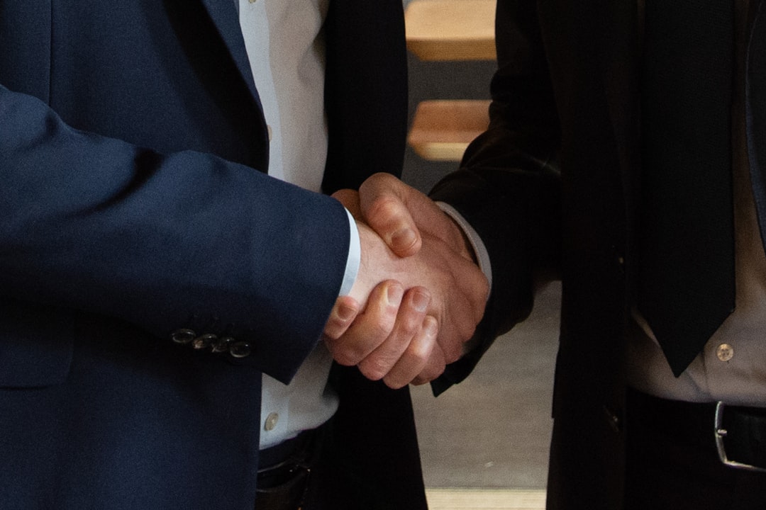 Business executives shaking hands on a deal, representing mergers and acquisitions - Corporate immigration law Business executives shaking hands on a deal, representing mergers and acquisitions - Corporate immigration law