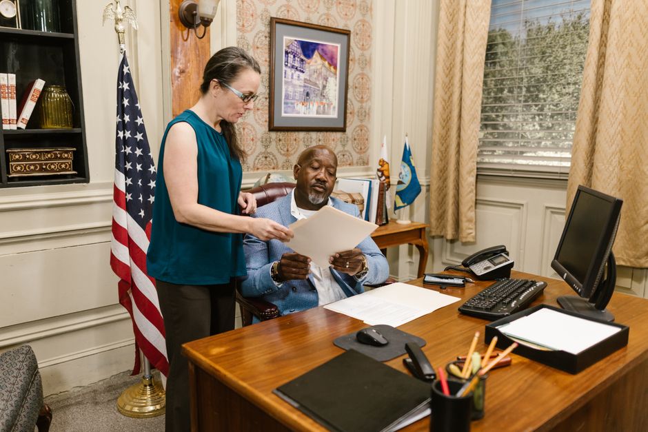 An immigration attorney reviewing documents with a client in a professional office setting - Green card application help An immigration attorney reviewing documents with a client in a professional office setting - Green card application help